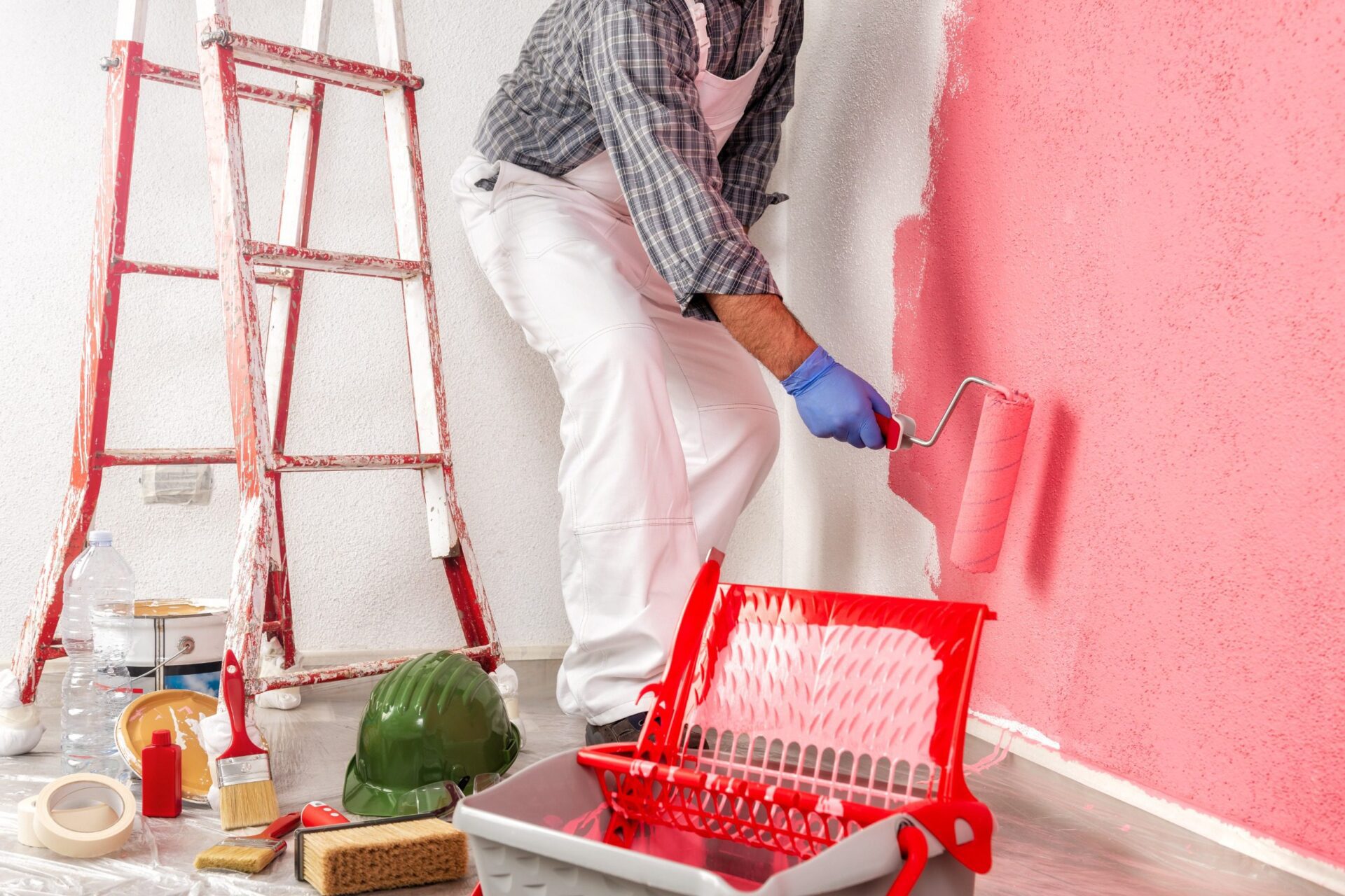 worker in white work overalls, with the roller painting the wall