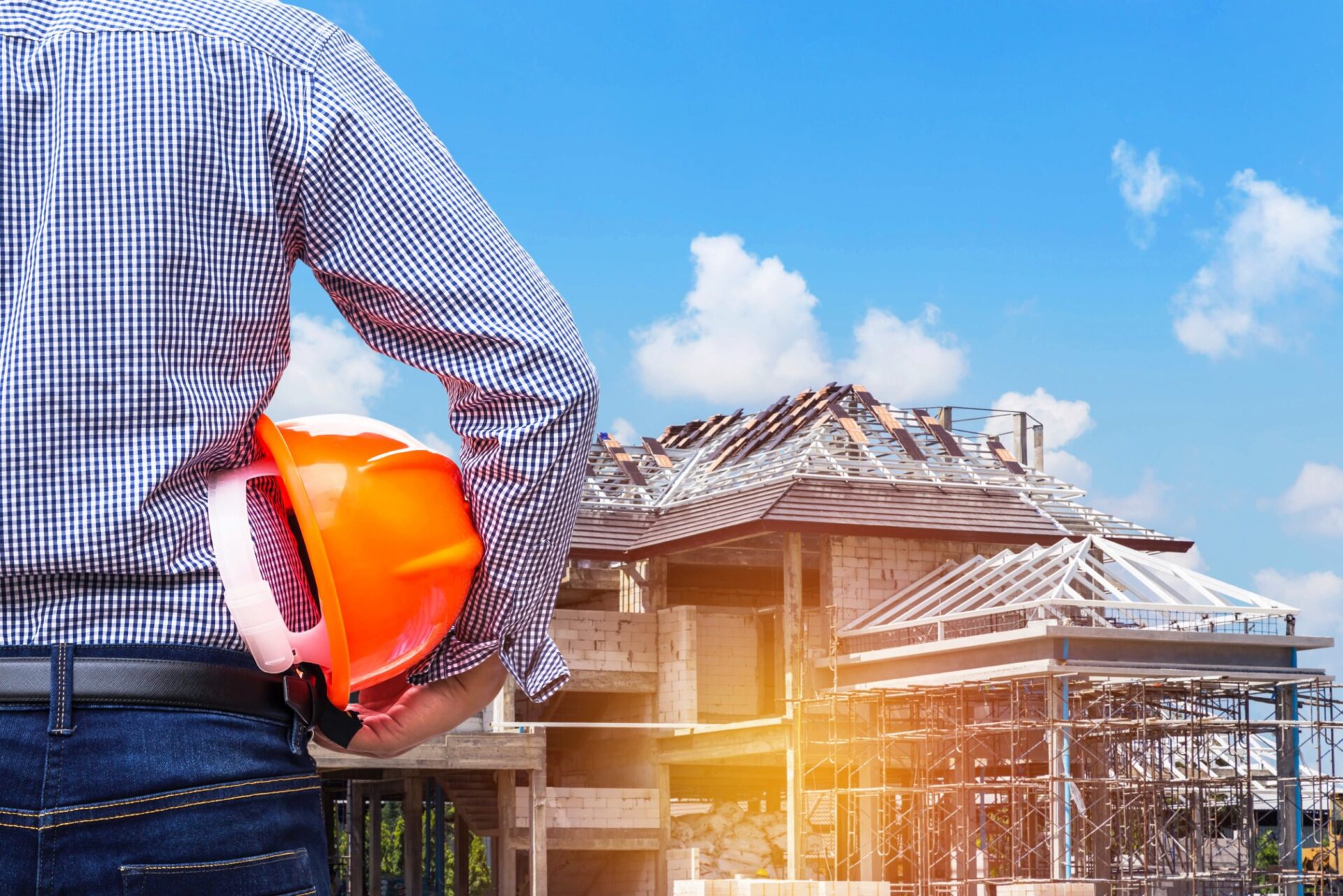 Engineer holding yellow safety helmet at new home building under construction site